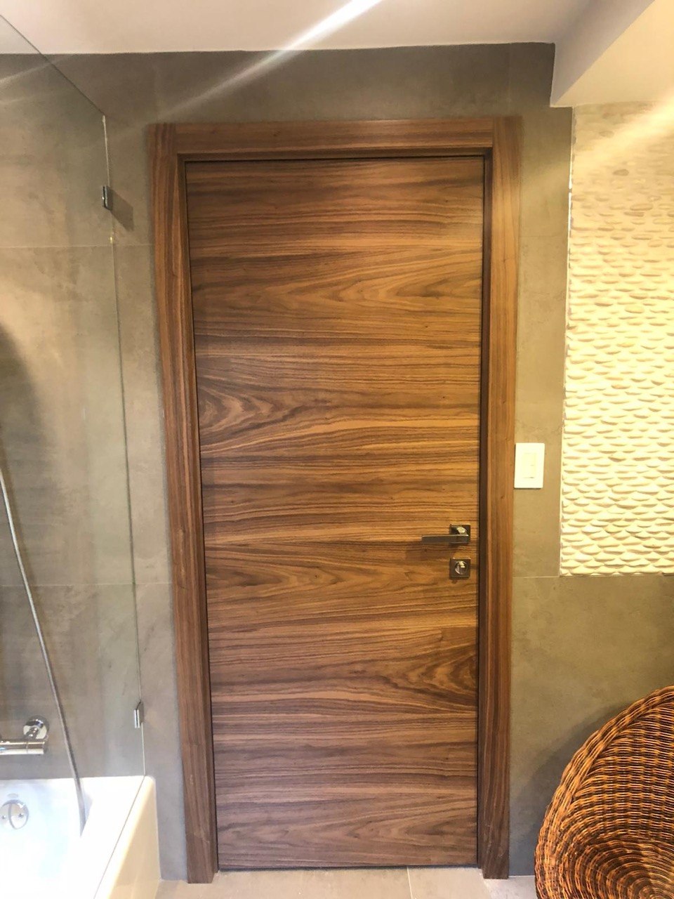 Walnut wood veneer interior door with horizontal grain in a modern bathroom
