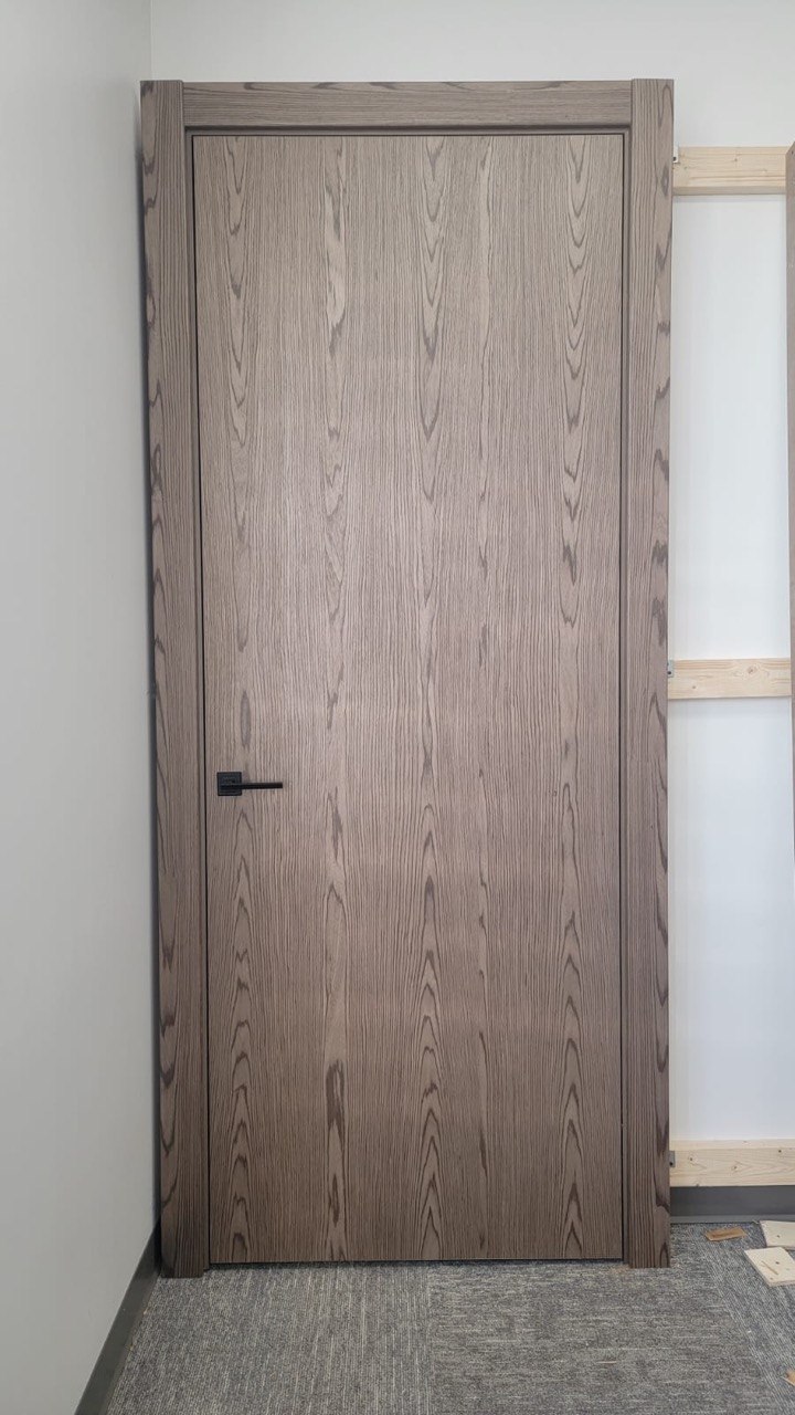 Smoked oak woodgrain flush interior door with a black lever handle