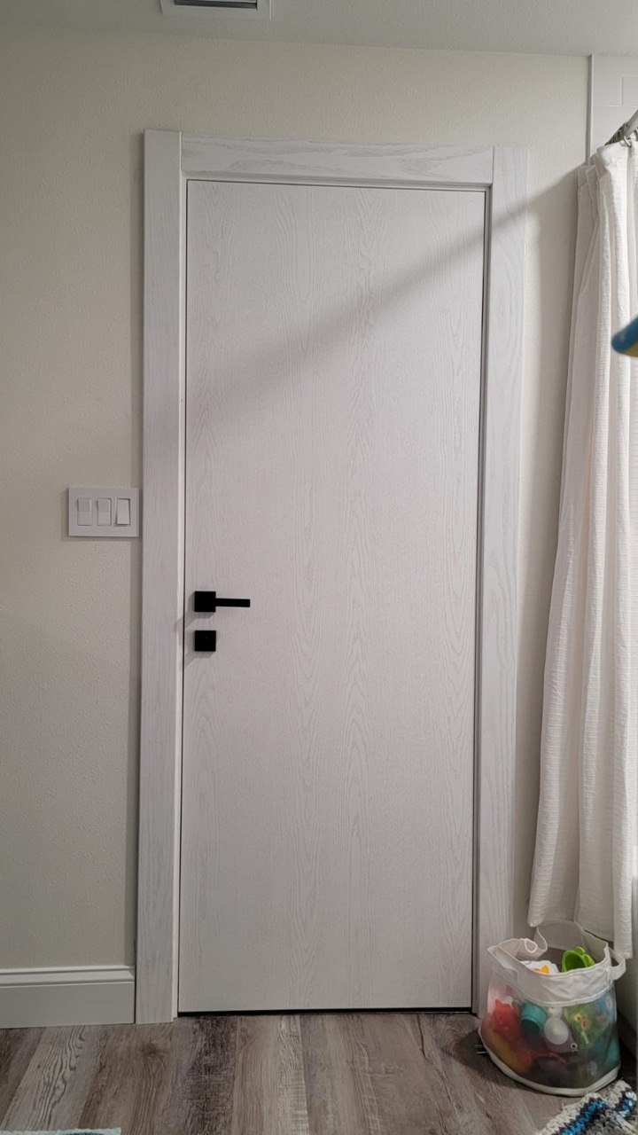 White woodgrain interior door with a matte-black lever handle