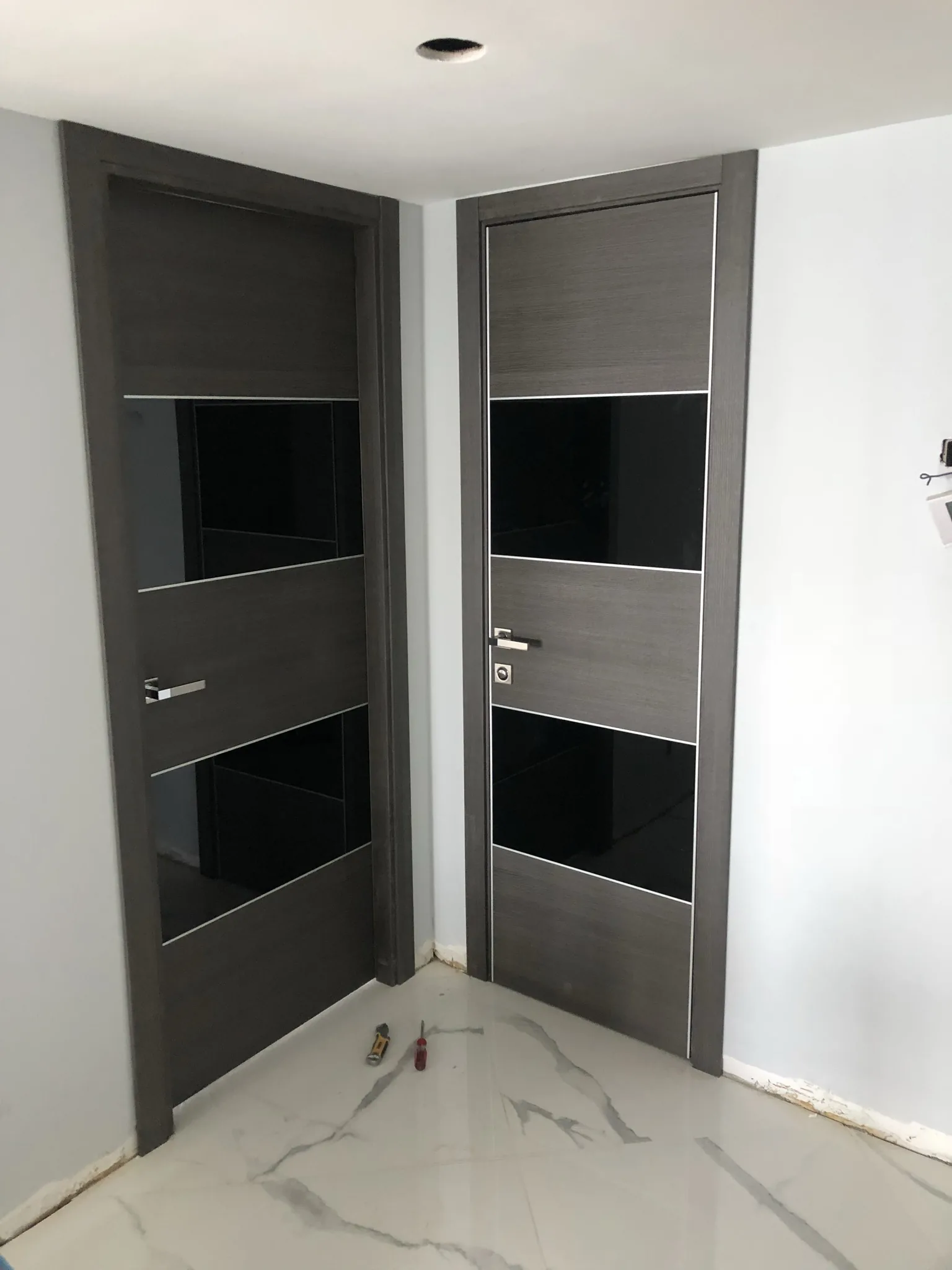 Grey woodgrain doors with black-glass panels — interior door supplied and installed by Slab & Trim