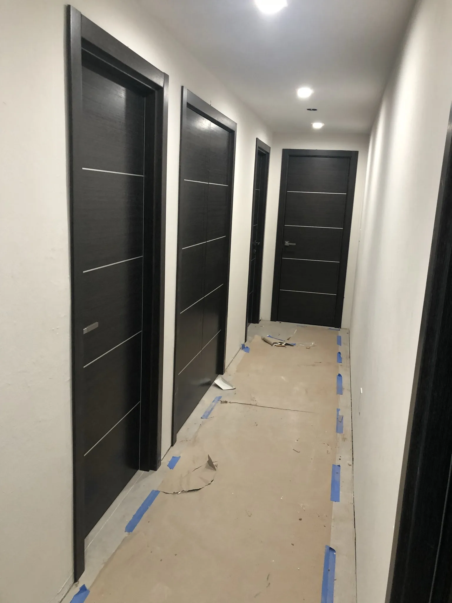 Wenge doors with aluminum inlays along a hallway — interior door supplied and installed by Slab & Trim