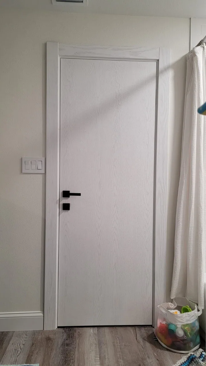White woodgrain interior door with a matte-black lever handle